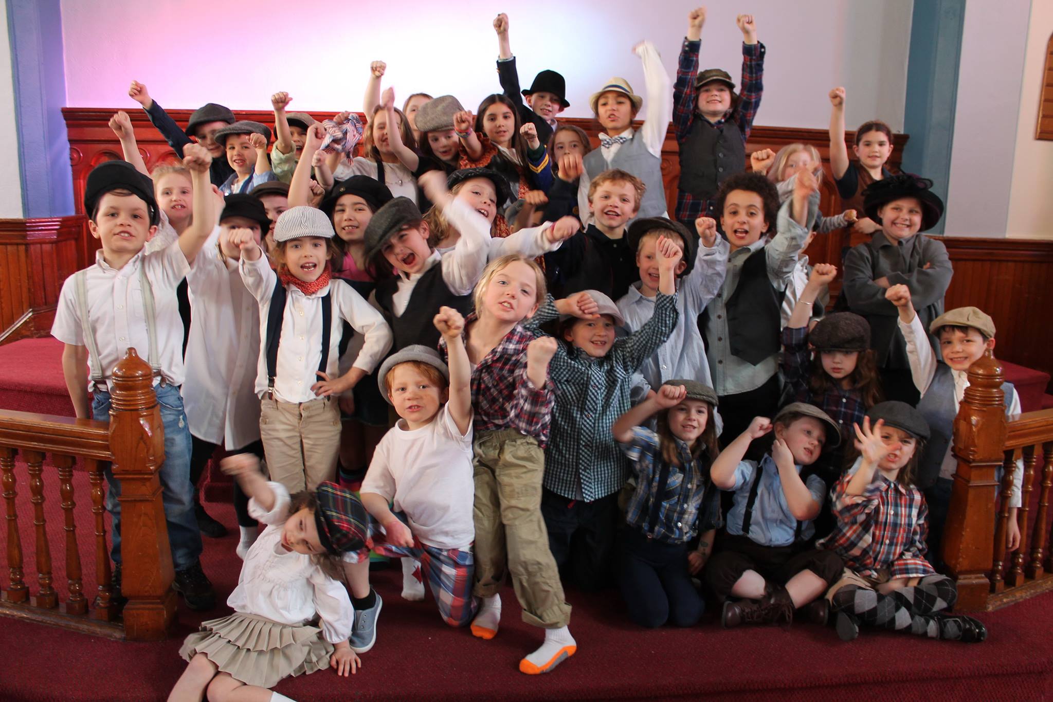A large cluster of young kids dressed as 1899 Newsies pose for the camera