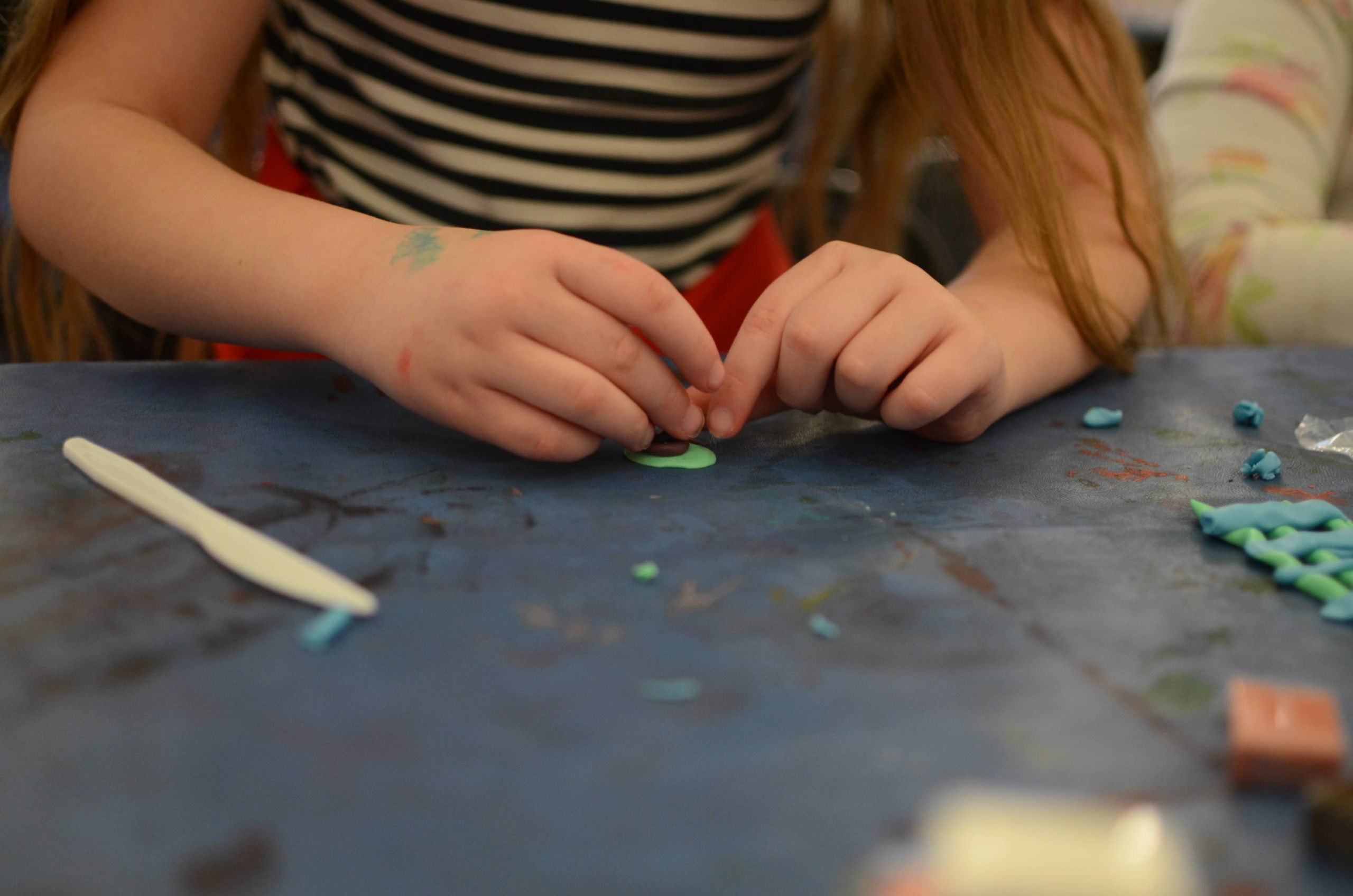 A young kid's hands carefully sculpt with colorful clay