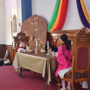 Two children sit at a large banquet table in royal robes