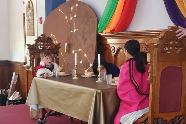 Two children sit at a large banquet table in royal robes
