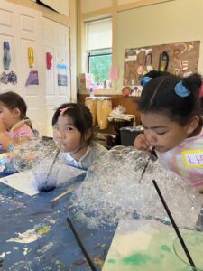 Kids blow bubbles with straws