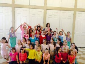 A group of about 30 kids poses in costumes for their final dance recital with Miss Kathy