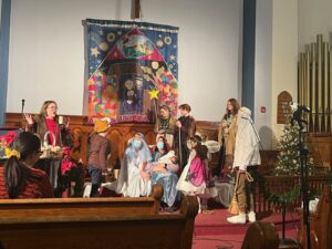 Christmas pageant with several kids of varying ages in Christmas costumes